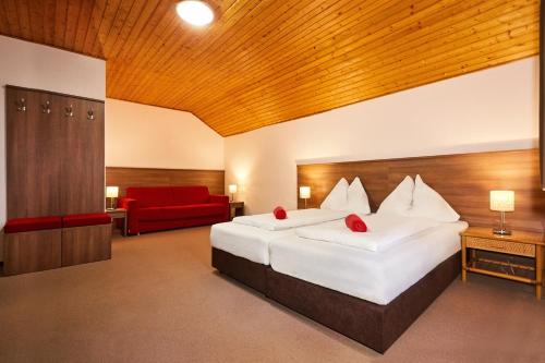 a hotel room with two beds and a red couch at Apartmány Nad Rybníkem in Železná Ruda