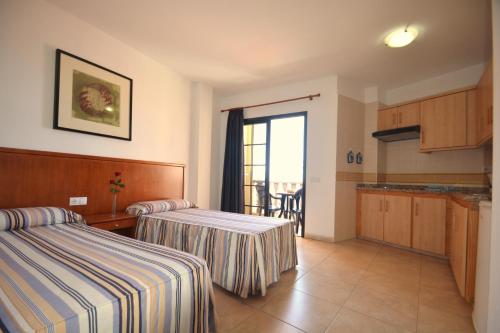 Habitación de hotel con 2 camas y cocina en Apartamentos Andrea, en Calera