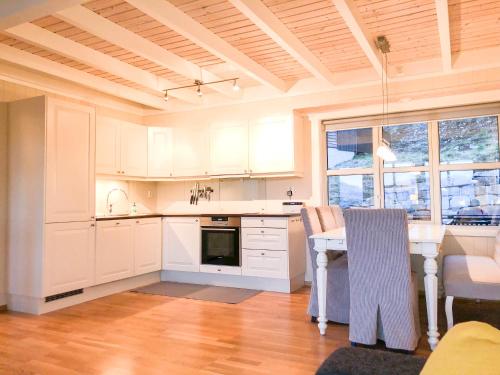una cocina con armarios blancos y una mesa con sillas. en Voss - Apartment with panoramic view, en Skulestadmo