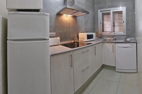 a kitchen with a white refrigerator and a sink at Viviendas Turisticas S'Estanyol in La Savina