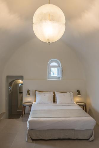 a bedroom with a large white bed and a light fixture at Art Maisons Oia Castle in Oia
