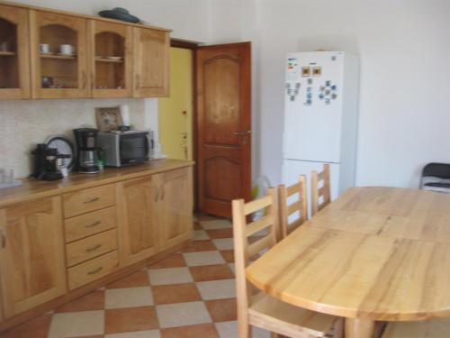 a kitchen with a wooden table and a white refrigerator at Casa Sidor in Baile Felix
