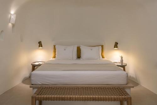 a bed with white sheets and pillows in a room at Art Maisons Oia Castle in Oia