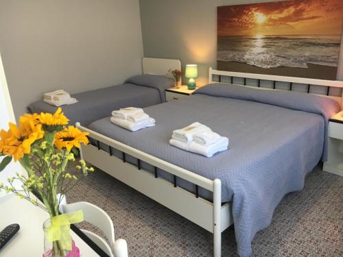 two beds in a bedroom with a vase of flowers at Hotel Gianna in Roseto degli Abruzzi