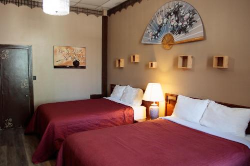 una camera d'albergo con due letti con lenzuola rosse di Hotel Casa Bella a Montréal