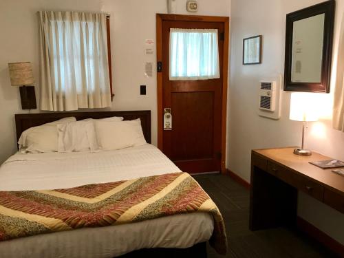 a bedroom with a bed and a desk with a lamp at Chalet Motel in Custer