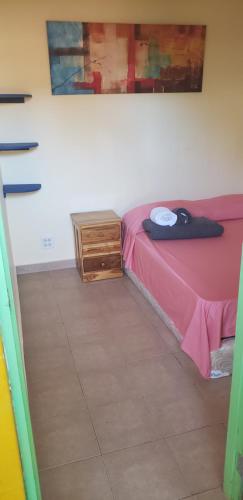 a bedroom with a pink bed and a wooden dresser at Hostel Mamallena in Panama City
