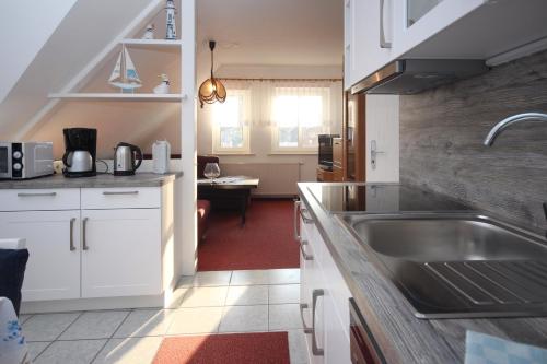 eine Küche mit weißen Schränken und einem Waschbecken in der Unterkunft Ferienwohnungen Thorsten Fründt in Prerow