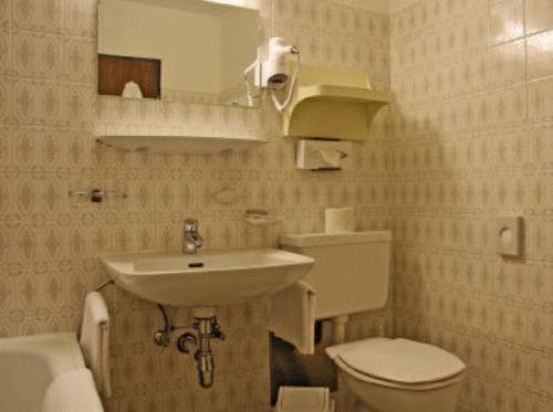 ein Badezimmer mit einem Waschbecken, einem WC und einem Spiegel in der Unterkunft Hotel Mooserkreuz in Sankt Anton am Arlberg