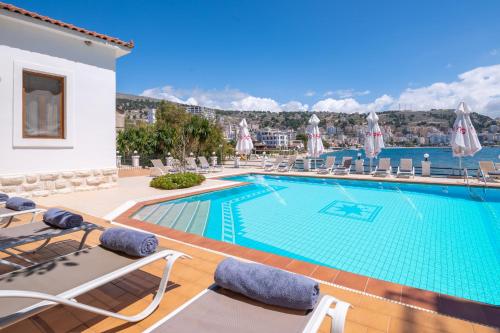 a swimming pool with chaise lounge chairs and a resort at PALMA city HOTEL in Sarandë