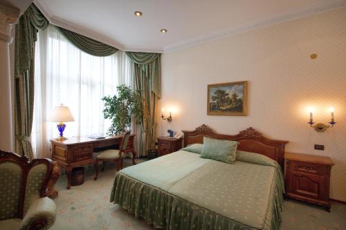 a hotel room with a bed and a desk and a desk at Grand Hotel London in Varna City