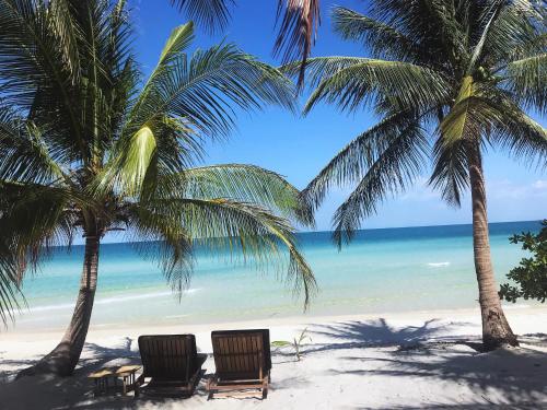 two palm trees and two chairs on a beach at Tamu Koh Rong in Koh Rong Island