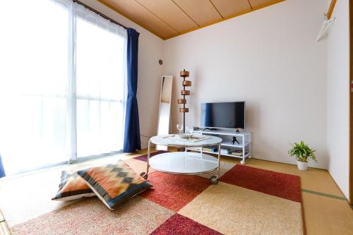 a living room with a table and a tv at Kappo INN Tokusa in Hashimoto