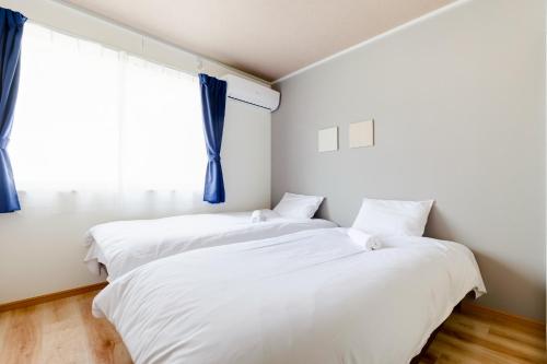 two beds in a room with a window at Kappo INN Tokusa in Hashimoto