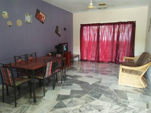 une salle à manger avec une table et des chaises et un rideau rouge dans l'établissement Marina View, Teluk Kemang, PD, à Port Dickson