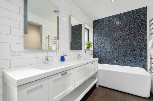 a white bathroom with a tub and a sink and a mirror at Maunga View in Queenstown