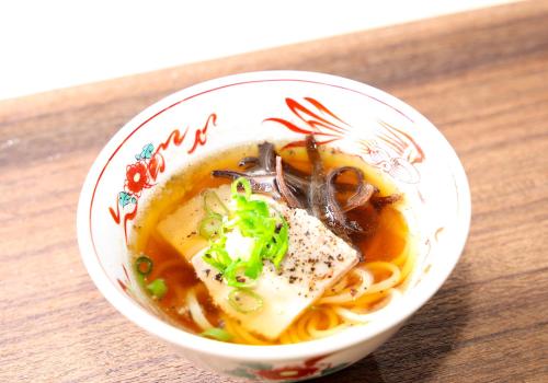 a bowl of soup with meat and noodles on a table at Daiwa Roynet Hotel Hiroshima-ekimae in Hiroshima