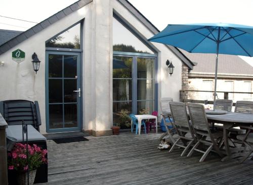 a patio with a table and chairs and an umbrella at Gîtes Les Myosotis in Morhet