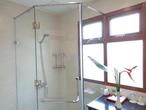 La salle de bains est pourvue d'une douche avec une porte en verre. dans l'établissement Vuon Xoai Resort, à Ấp Phước Cang