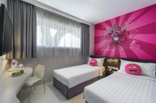 a hotel room with two beds and a pink wall at favehotel Gatot Subroto Jakarta in Jakarta