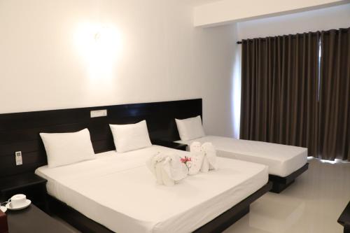 two beds in a hotel room with towels on them at Tangalle Rest House in Tangalle
