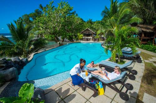 un grupo de personas sentadas en una silla de jardín junto a una piscina en Seabreeze Resort Samoa – Exclusively for Adults en Aufaga