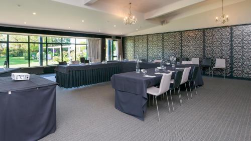 a dining room with tables and white chairs and windows at Croydon Lodge in Gore