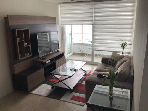 a living room with a couch and a television at Moderno departamento Miraflorino con aire acondicionado in Lima