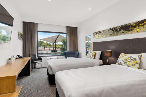 a hotel room with two beds and a desk at Quality Hotel Rules Club Wagga in Wagga Wagga