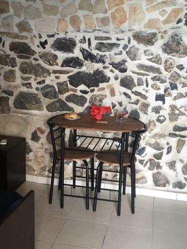 a wooden table with two chairs and a stone wall at Mariaeva Rooms in Léntas