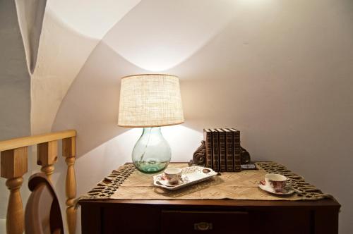 a table with a lamp and two cups on it at Home Holiday Salento Casa Agrosì in Supersano