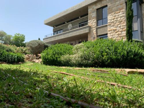 a building with a grass yard in front of it at Villa Pnai in Rosh Pinna