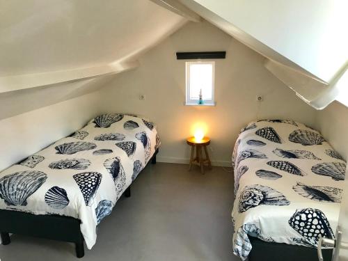 two beds in a attic bedroom with a window at Ferienhaus Glücklich am Meer 3 mit Wellnesszugang in Egmond aan Zee