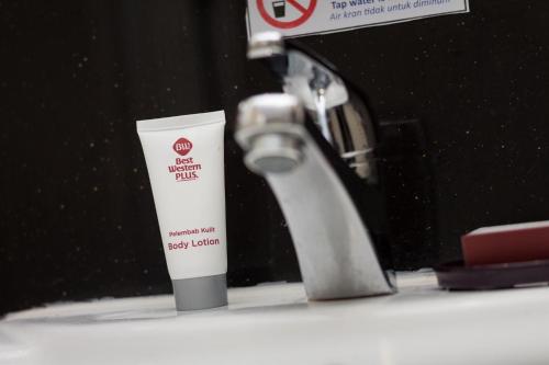 a tube of sunscreen sitting next to a bathroom sink at Best Western Plus Makassar Beach in Makassar