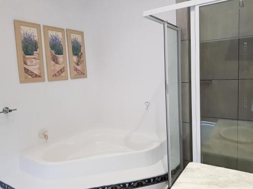 a bathroom with a tub and three pictures on the wall at Zonnevanger Guesthouse in Noorder-Paarl