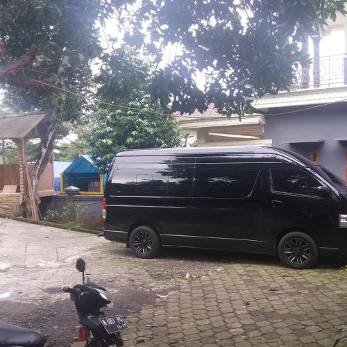 a black van is parked next to a scooter at Budhis Home in Bromo