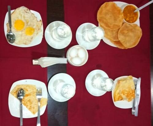 a table with plates of food and eggs and bread at Hotel Grand Luit in Guwahati