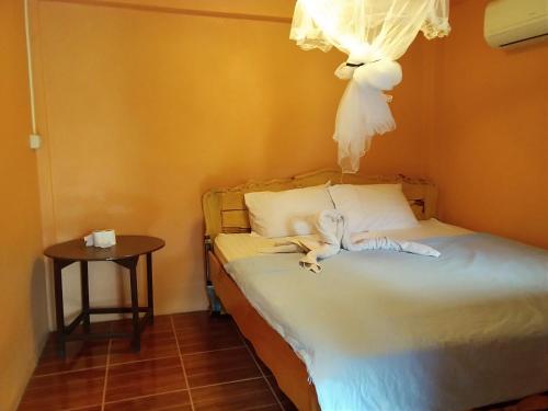 a bedroom with a bed with white sheets and a table at Ok Sukhothai Resort in Sukhothai