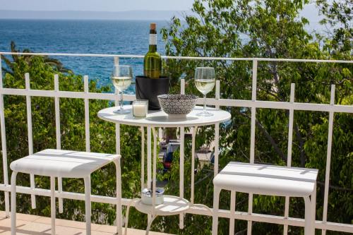 a table with a bottle of wine and two chairs at Apartments Coast 27 in Podgora