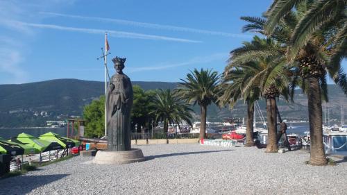 a statue of a woman standing next to palm trees at Apartments Astoria HN in Herceg-Novi