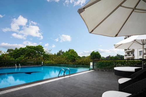 a swimming pool with an umbrella and a patio at Elegant Suites Westlake in Hanoi