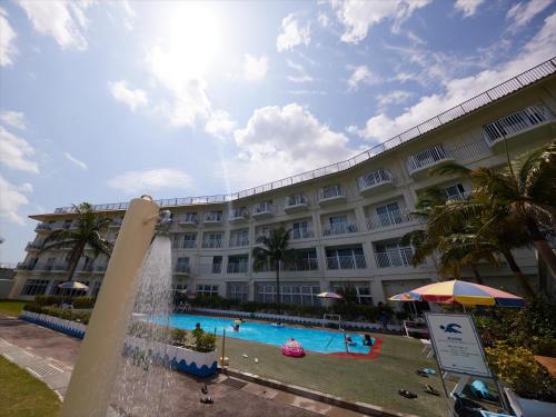 un grand bâtiment avec une piscine et une fontaine dans l'établissement Miyuki Hamabaru Resort, à Onna