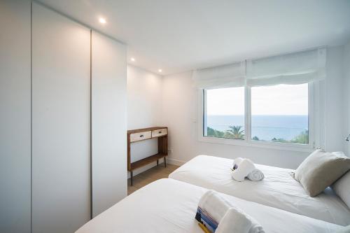 - une chambre blanche avec une fenêtre et 2 lits dans l'établissement Boutique Ocean Terrace Luxury - SSHOUSING, à Saint-Sébastien