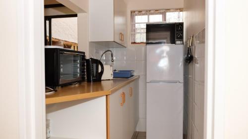 a kitchen with white cabinets and a refrigerator at Crowned Crane in Gonubie