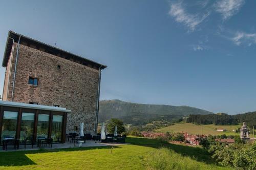 a building with a view of a field and mountains at Hotel Torre Zumeltzegi in Oñate
