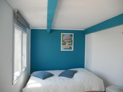 - une chambre avec des murs bleus et un lit avec deux oreillers dans l'établissement Ô Bord de Mer !, à Hyères