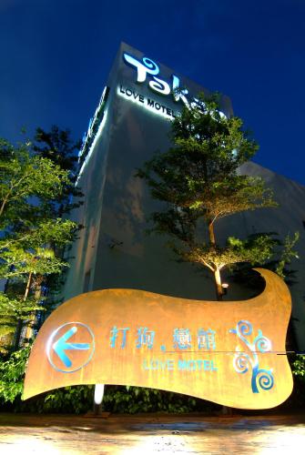 a sign in front of a building with a tree at Takao Love Motel in Kaohsiung