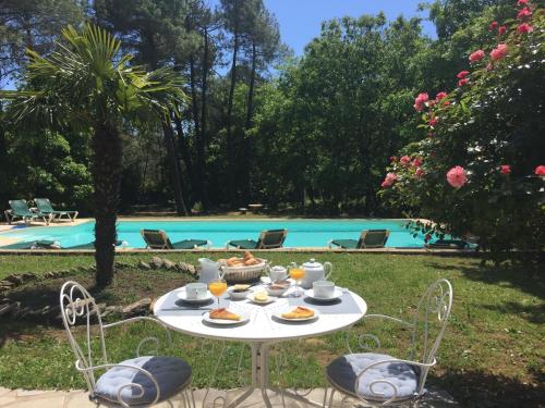 een tafel met eten erop naast een zwembad bij Le Clos des Cigales in Roussillon