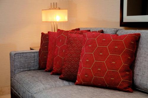 a couch with four red pillows on it at 76 Friends Colony in New Delhi