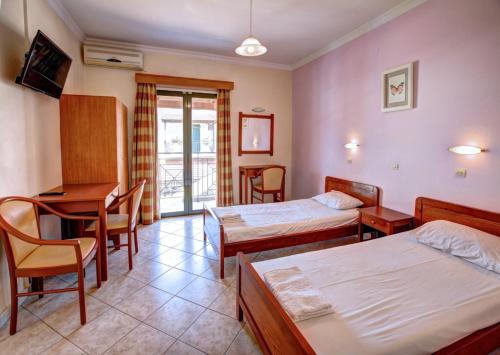 a hotel room with two beds and a table and chairs at Trident Studios and Apartments in Kavos
